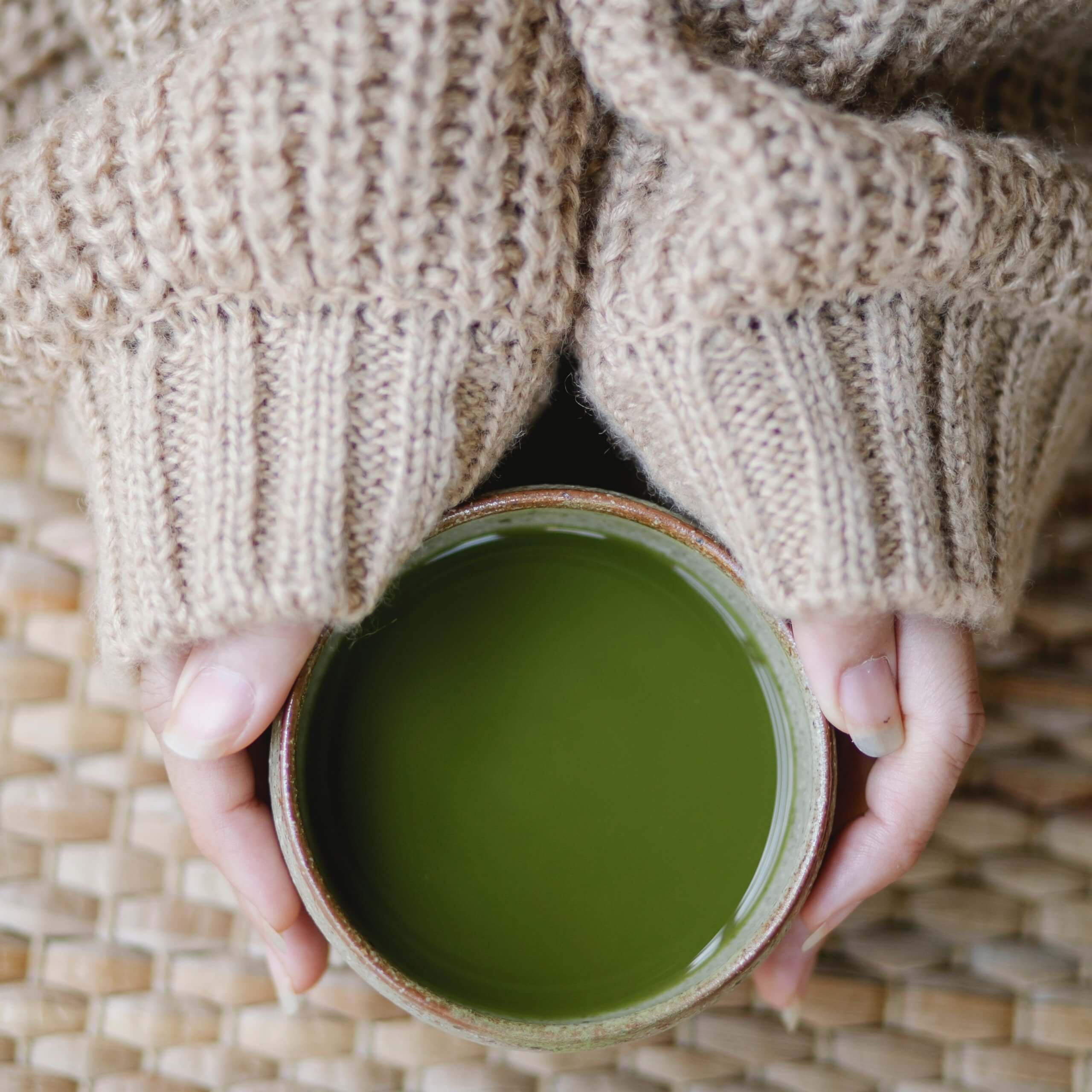 A woman holding a cup of matcha tea.