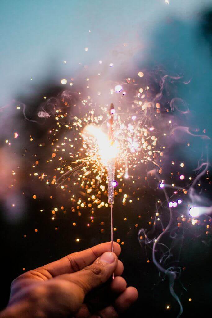 A person holding a lit sparkler, symbolizing the magic of manifestation.