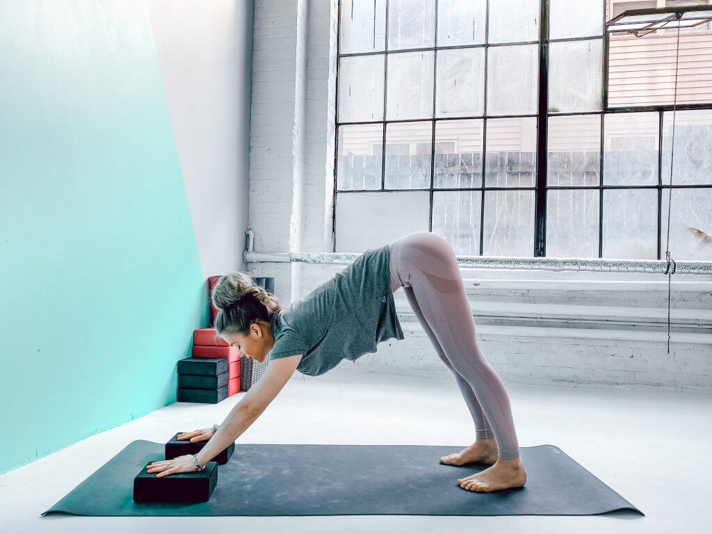 Woman using two yoga blocks under her hands for a modified Downward Dog.