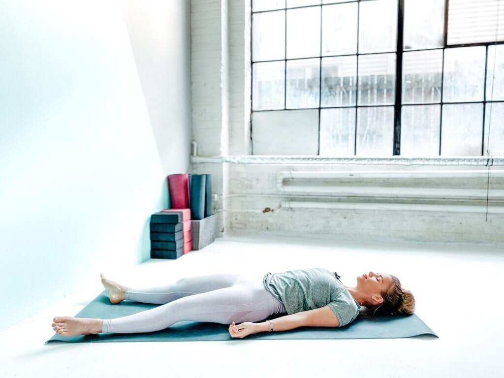 Woman resting in Corpse Pose.