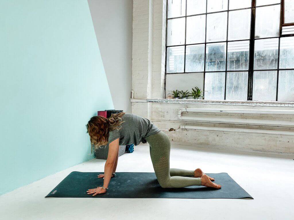 Woman demonstrating Cow Pose, arching the back.