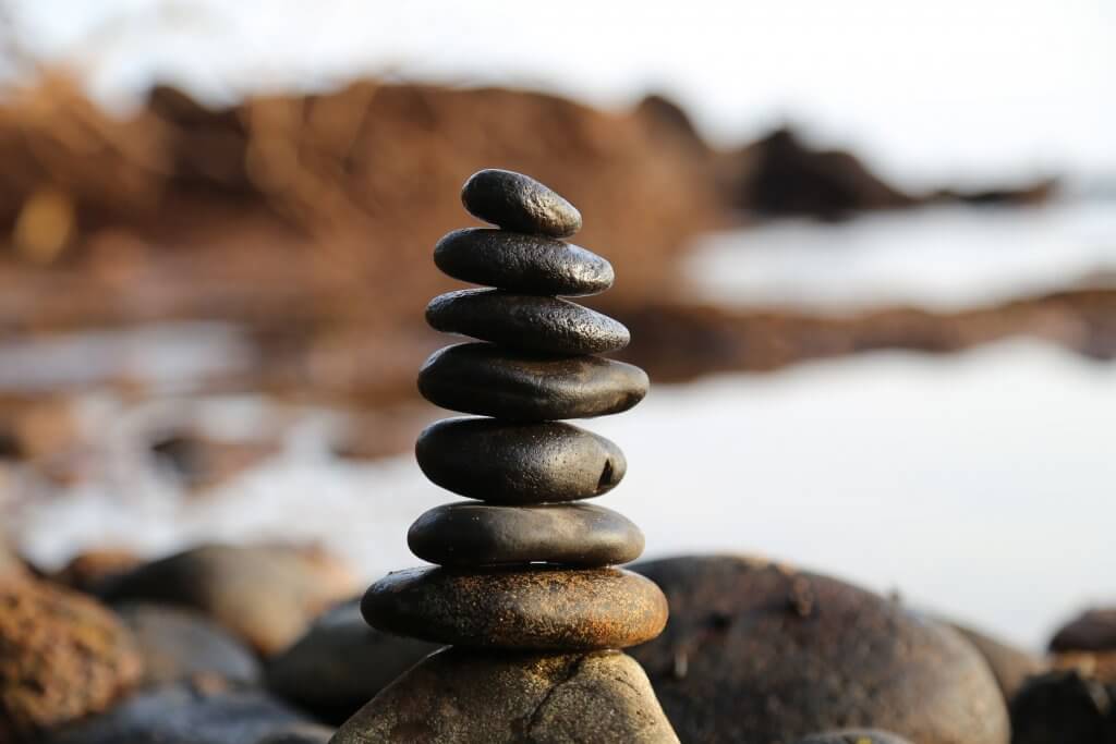 A silhouette of a person balancing on a rock against a sunset.
